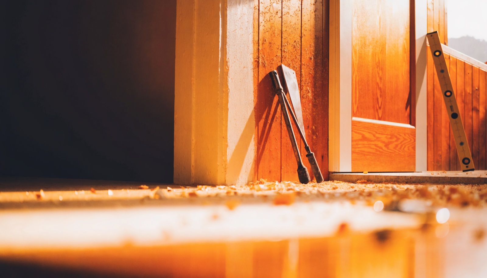 Sunlight falling across a timber door frame and shavings on a workshop floor