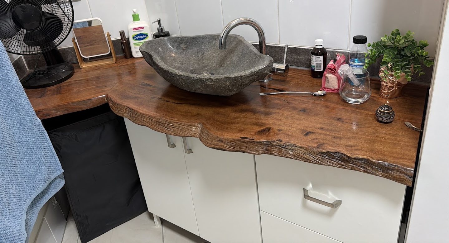 A live-edge timber vanity top with a carved stone basin sitting on it