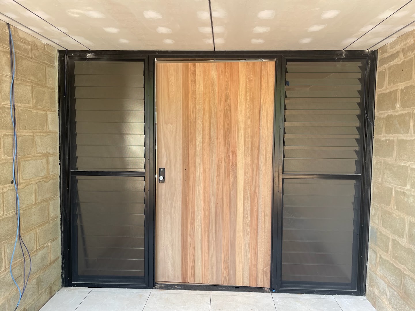 A timber entry door hung beside a matching sidelight and louvre panel