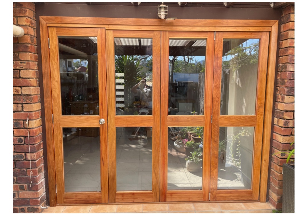 A timber cabinet with glazed french-style doors set into a brick wall