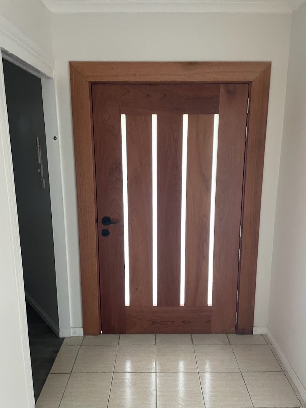 A dark stained timber entry door with four narrow vertical glazed slots