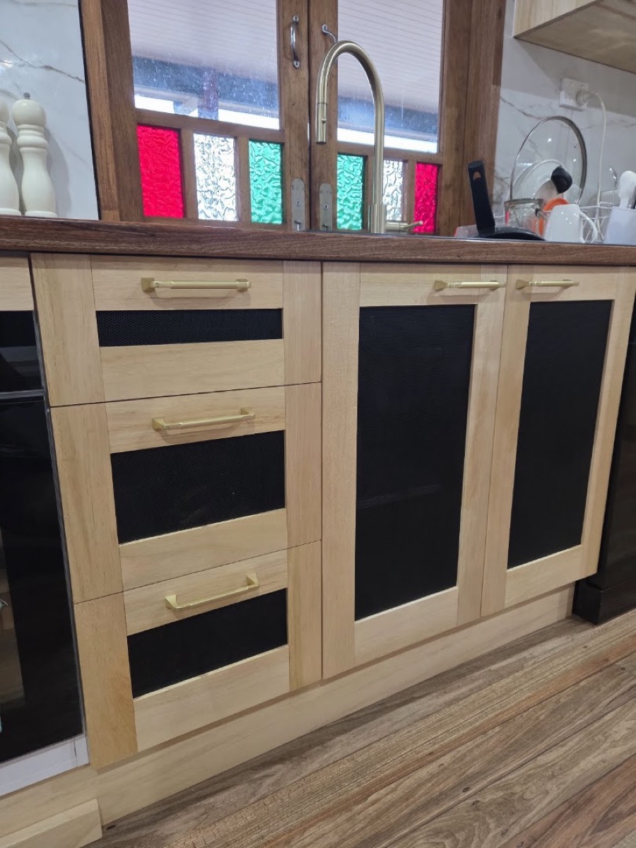 A timber sideboard with glazed upper doors against a brick wall