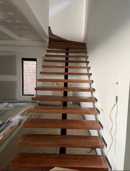 An open-riser timber staircase with slim treads against a white wall