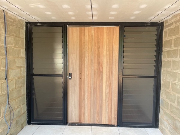 A timber entry door with a matching sidelight and louvre panel