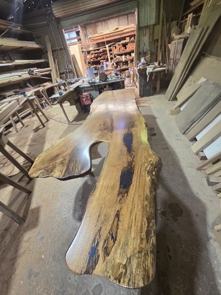 A live-edge timber slab bench standing in the workshop