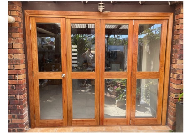 A timber cabinet with glazed french-style doors set into a brick wall