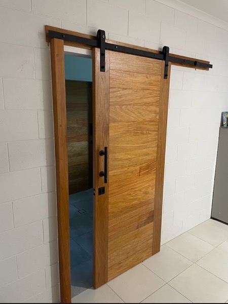 A timber barn-style sliding door on a black rail across a doorway