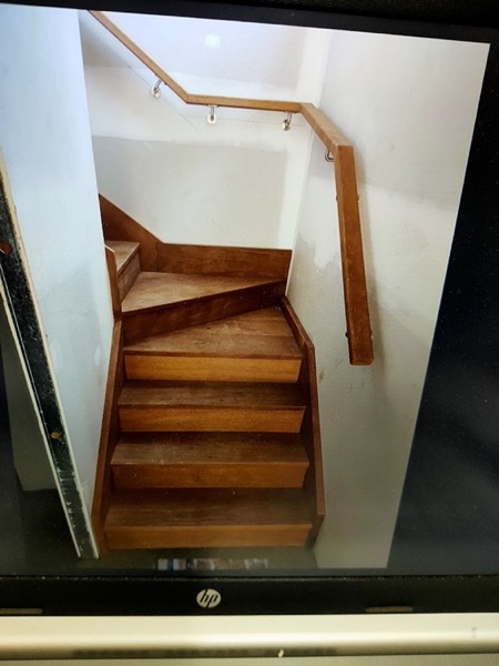 A timber staircase turning at a landing with a shaped handrail