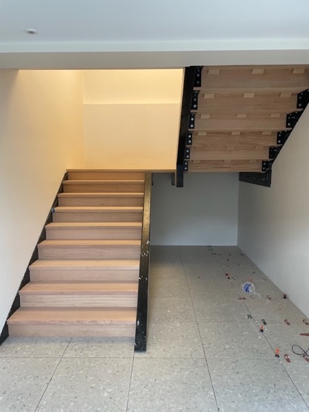 Timber treads on a steel stringer rising over a tiled floor