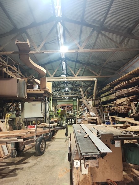 The inside of the workshop, machinery in the centre and timber racked to the roof