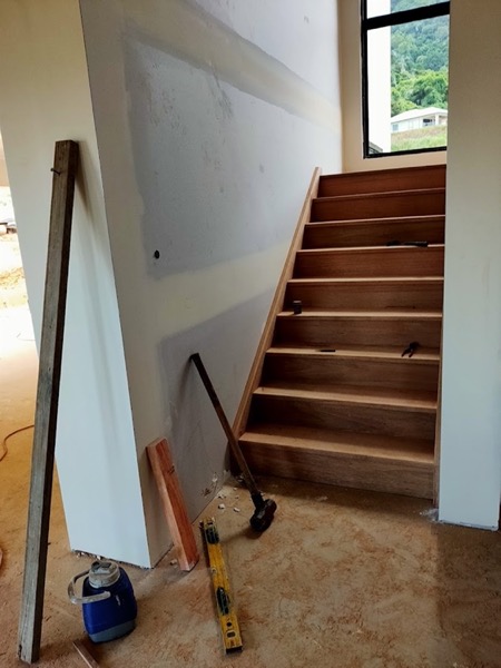 A timber staircase part way through installation against a bare wall